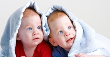 Beautiful redheaded twin babies under blanket