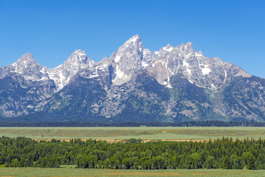 Panoramic photograph of the Grand Teton mountain range in summer with a pine tree forest, Grand Teton National Park, Rocky Mountains, Wyoming, United States of America (USA)